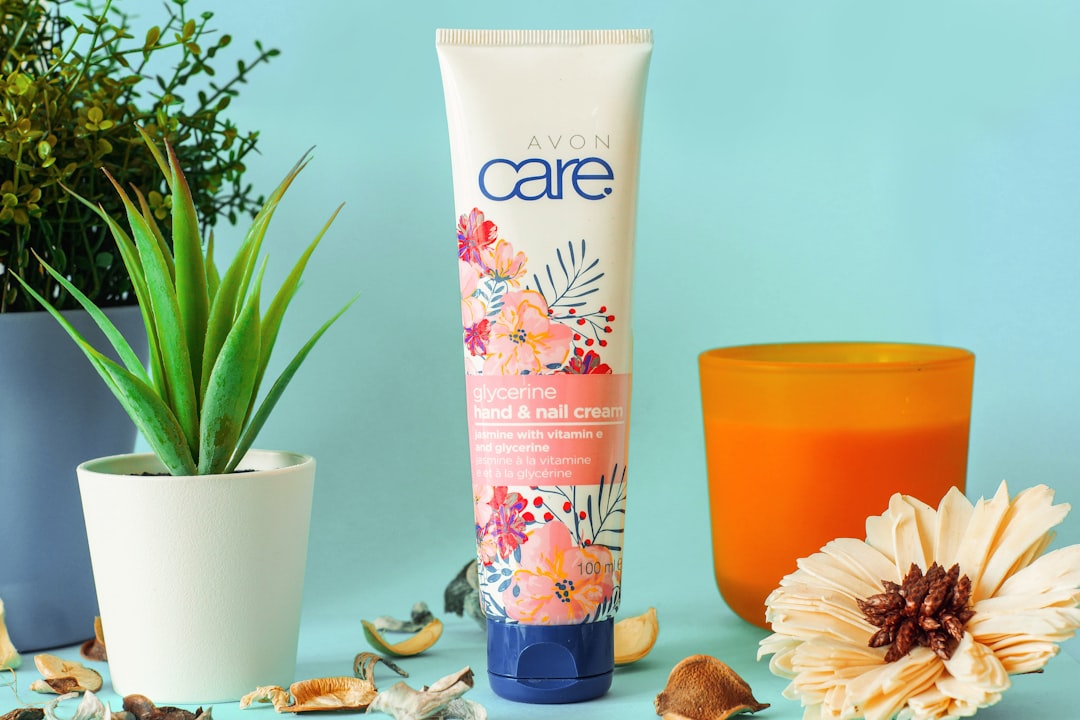A person applying moisturizer on their face in a sunny outdoor setting, showcasing healthy skin care practices.